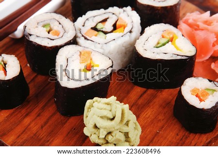 Japanese Cuisine : Sushi Maki Roll with Salmon and tuna inside . on wooden plate with wasabi and ginger isolated over white background