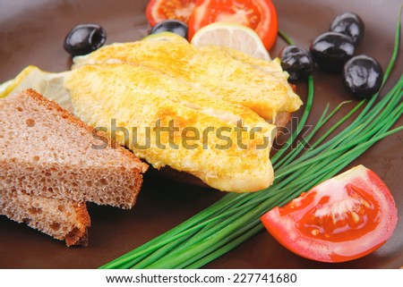 grilled fish fillet served with tomatoes,olives and bread . no people. shallow dof