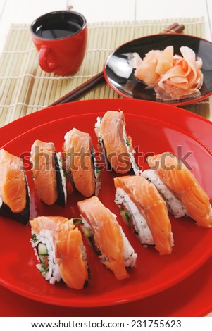 japanese cuisine onigiri sashimi inside out sushi rolls with ginger and sake cup on red plate over white wooden table