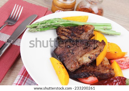 meat food : rare medium roast beef fillet with mango tomatoes and asparagus , served on white dish on red table map over wooden table