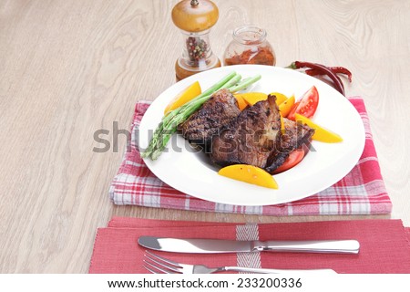 meat food : rare medium roast beef fillet with mango tomatoes and asparagus , served on white dish on red table map over wooden table