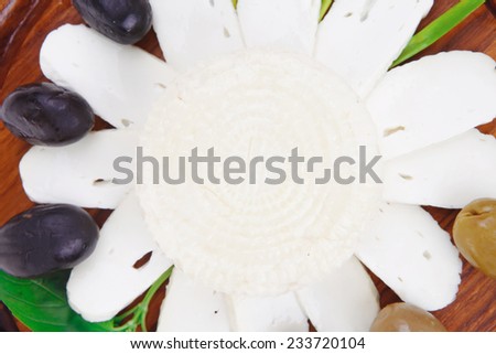 dairy products : feta white cheese sliced on cut board with olives and basil leaves isolated over white background
