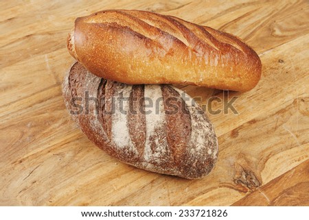 different rye and white flour french bread loaf with on light wooden table background