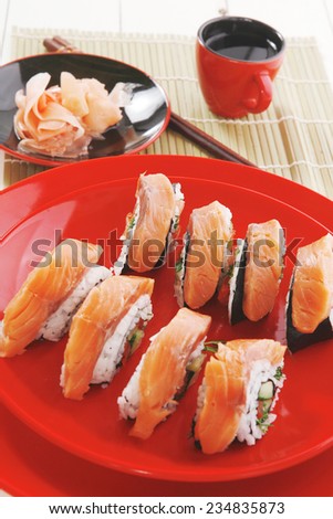 japanese cuisine onigiri sashimi inside out sushi rolls with ginger and sake cup on red plate over white wooden table