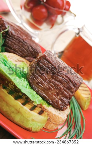 savory food : roast beef garnished with vegetables , juice and olives on red plate over wooden table