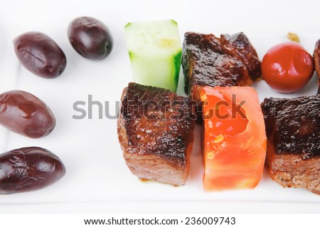 european food: grilled beef meat on white china plate isolated on white background with olives and tomatoes