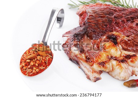 meat food : grilled beef steak on white plate with red thin pepper , spices and rosemary isolated over white background