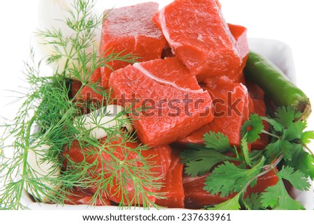 slices of raw fresh beef meat fillet in a white bowls with dill and green peppers isolated over white background