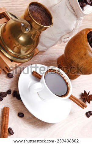 sweet hot drink : black turkish coffee in small white mug with mortar and pestle , coffee beans in white bag , copper old style cezve full hot coffee, decorated with cinnamon sticks and anise stars
