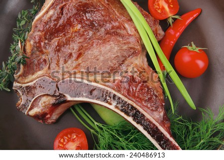 meat food : roast rib on dark dish with thyme pepper and tomato isolated over white background