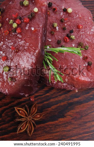 fresh raw beef fillet mignon on old retro style wood as background with rosemary peppercorn and salt