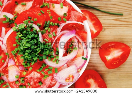 healthy food : fresh tomato salad in white bowl with bunch of chives and raw tomatoes on twig , onion,  over wooden table