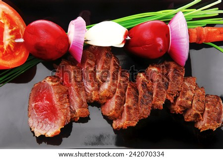 meat savory : roasted bbq meat served on black plate with vegetables on spit isolated on white background