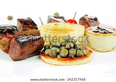 european food: roast beef meat goulash over white plate isolated on white background, with hot pepper, capers and sauces