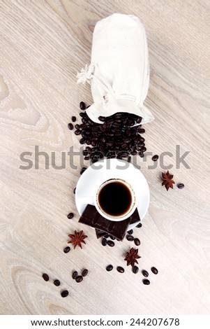 sweet hot food: black coffee with dark chocolate and coffee beans in bag on wooden table