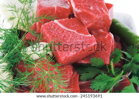 raw fresh beef meat slices in a white bowls with dill and green hot peppers isolated over white background