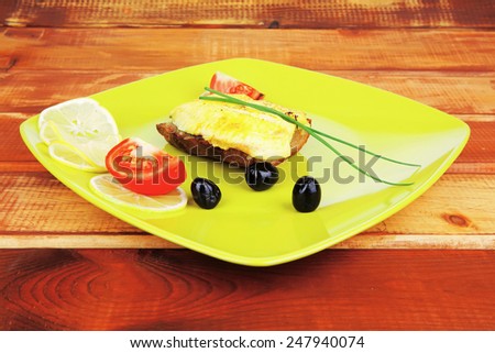 fish fillet with greek olives,tomatoes,chives and lemon over wood
