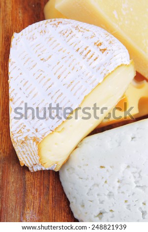 various types of solid french cheese parmesan brie and edam on wooden platter isolated on white background