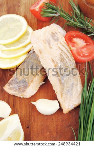 sea food : roasted pink salmon fillet with chinese onion, cherry tomatoes pieces , rosemary twigs and lemon on wooden board isolated over white background