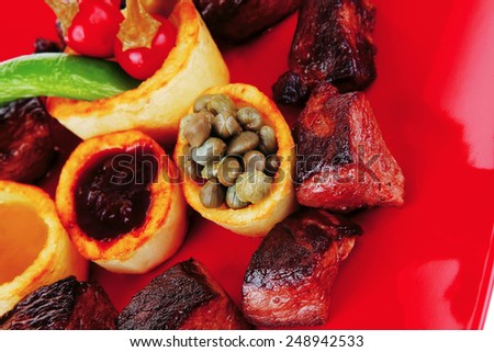 european food: roast beef meat goulash over red plate isolated on white background with tomatoes and dill and bbq sauce
