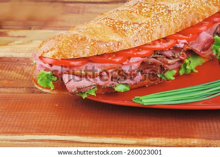 french sandwich on red plate : long baguette with smoked chicken sausage with sauces over wood