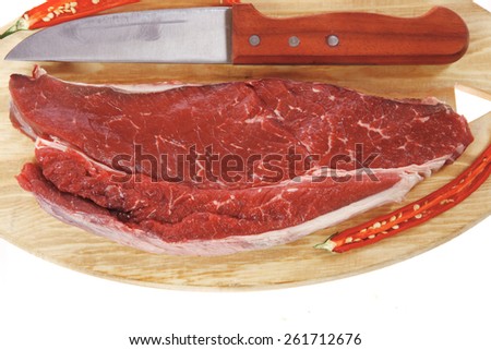 fresh raw beef fillet with red hot chili pepper and knife on wooden plate isolated over white background