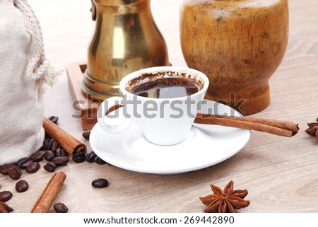 sweet hot drink : black arabic coffee in small white cup with mortar and pestle , bag full beans, copper old style cezve , decorated with cinnamon sticks and anise stars
