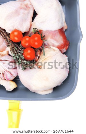 raw chicken legs with tomatoes and thyme on yellow ceramic pan ready to cooking isolated on white background