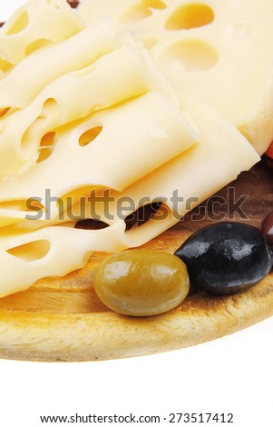 yellow swiss cheese sliced on wooden platter with olives and tomato isolated over white background