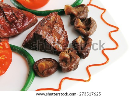served grilled beef fillet mignon entrecote on a white plate with mushrooms and tomatoes on plate isolated on white background