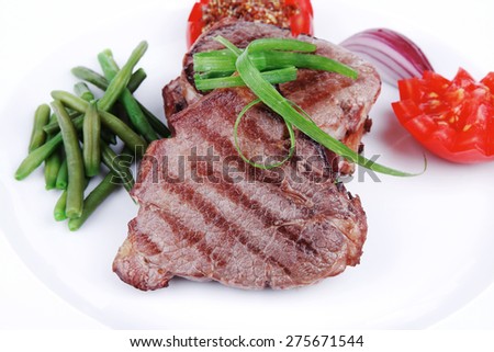 roasted beef meat strips steak on white ceramic plate with sweet pea and tomatoes isolated over white background