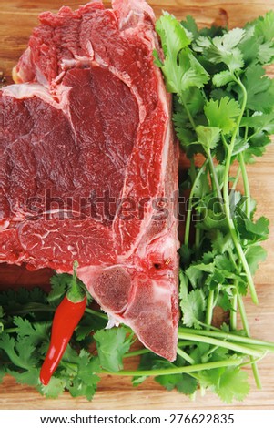 butchery : fresh raw beef lamb big rib ready to cooking with green stuff on wooden plate isolated over white background