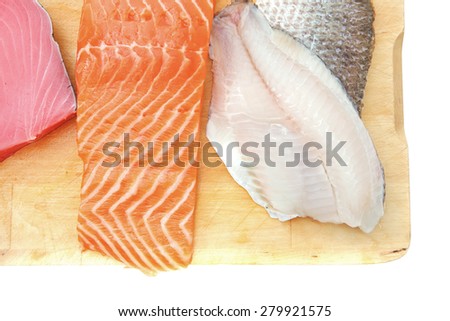 raw set of sea fish food : salmon , red tuna, and sole fish chunks served on wooden plate isolated on white background