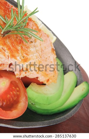 healthy diet food: hot sea grilled  red salmon fish fillet with lemon avocado and tomatoes on metal pan over wooden plate isolated on white background