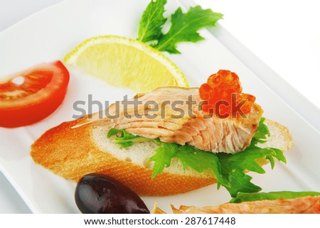 healthy appetizer : sandwich with sea salmon and red caviar, olives, tomato and lemon on white china plate isolated over white background