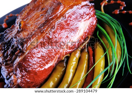 roast red beef meat bbq bloc served on black plate  with green chives adn red hot pepper on black plate isolated over white background