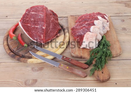 fresh raw beef meat steak and chunk with red hot pepper and dill on wooden cut plates over table