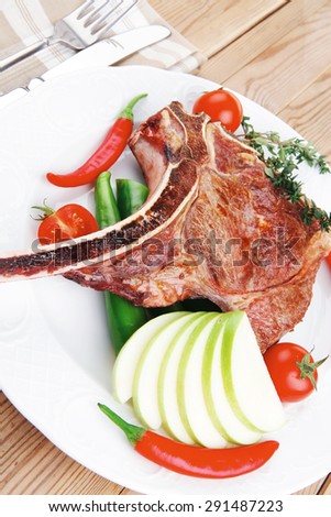 savory : roasted beef spare rib on white dish with cutlery thyme pepper and tomato on wooden table