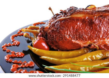 roast red beef meat bbq block served on black plate  with green chives and red hot pepper on black plate isolated over white background