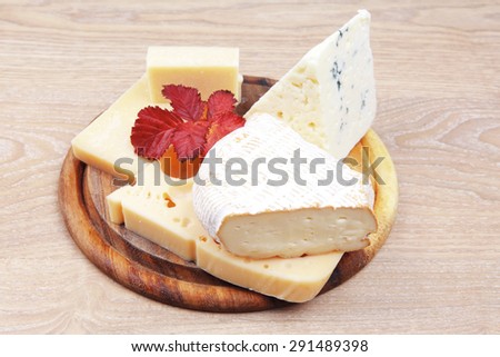 edam parmesan and brie cheese on wooden platter over wooden table