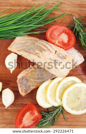 savory sea fish entree : roasted salmon fillet with green onion, red cherry tomatoes pieces , rosemary twigs and lemon on wooden board isolated on white background