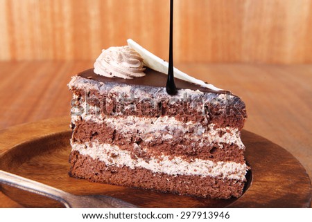 sweet brownie chocolate cream cake topped with white chocolate and cream with chocolate with chocolate sauce on wooden background