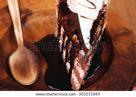 sweet brownie chocolate cream cake topped with white chocolate and cream with chocolate with chocolate sauce on wooden background