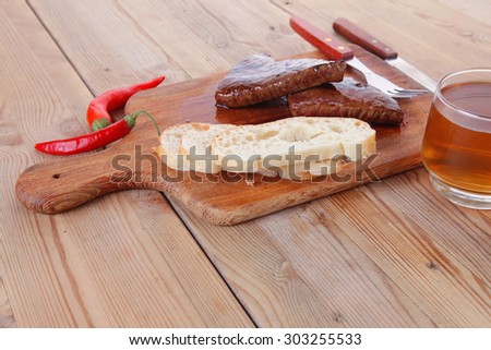 fresh beef meat steak with red hot pepper and bun slices served on plate with whiskey on wood over table with cutlery