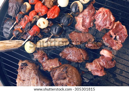 fresh raw beef fillet steak red meat with tomatoes and eggplant on skewers on big round barbecue brazier grid full with ready charcoal