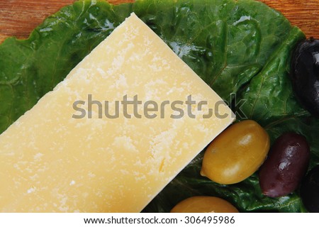 parmesan cheese on wooden platter with olives and tomato isolated over white background