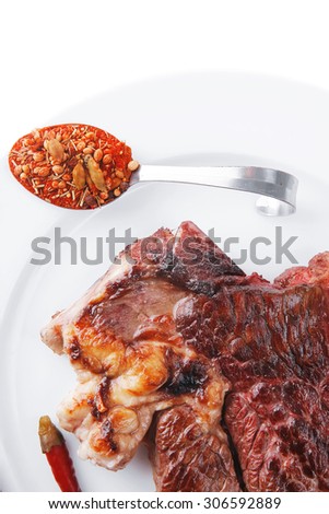 meat food : roasted steak on white plate with red thin chili pepper and spices isolated over white background