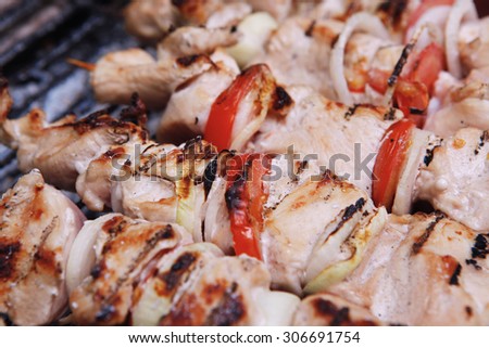 fresh turkey pink brisket shish kebab on wooden skewers with tomatoes over barbecue brazier full burned charcoal