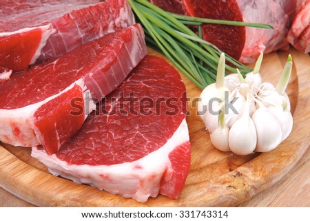 raw meat : fresh beef pork big rib and fillet with garlic and green stuff on wood isolated over white background