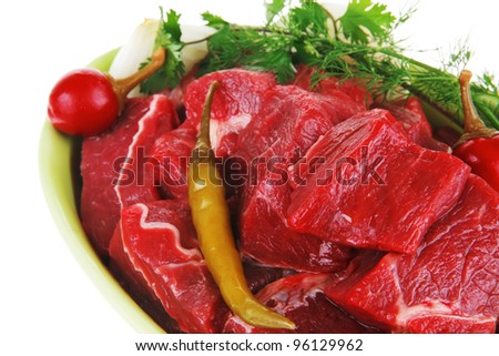 uncooked fresh beef meat chunks on ceramic bowls with vegetables and red peppers isolated over white background